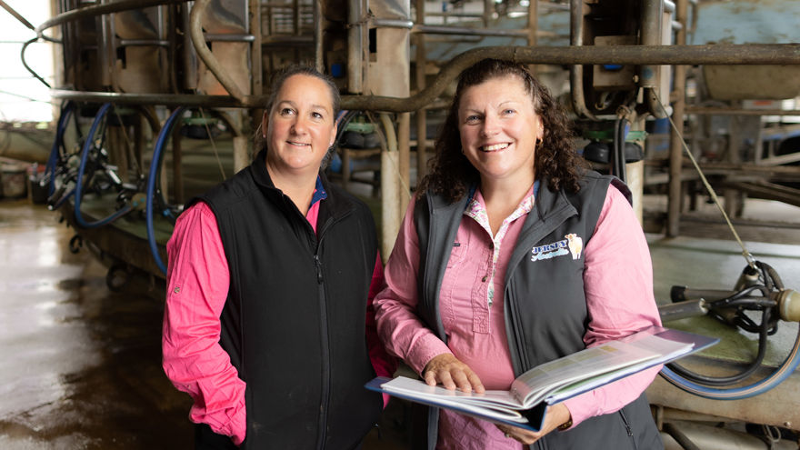 Two women in pink shirts, one is holding a folder
