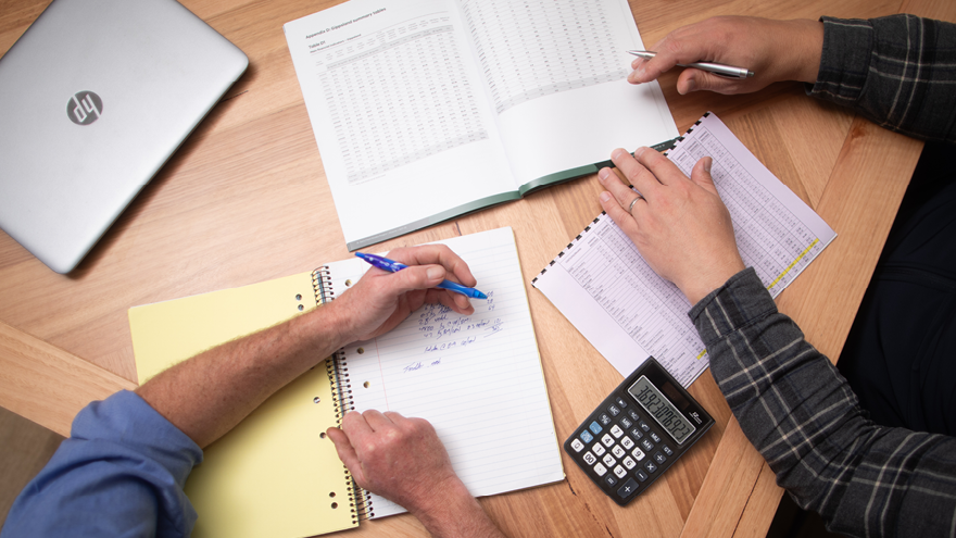 Two farmers are reviewing their farm business performance on a dinning table.