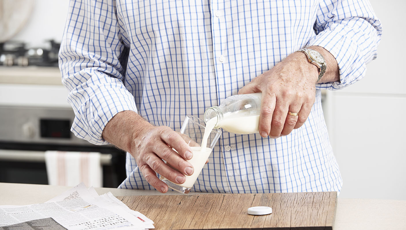 person pouring milk into a glass