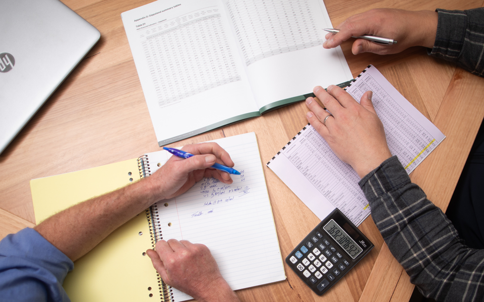 Two farmers are reviewing their farm business performance on a dinning table.